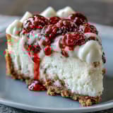 Fresh raspberry garnish and white chocolate shavings top a whole Indulgent White Chocolate Raspberry Cheesecake Bliss with a golden graham cracker crust.