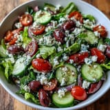Colorful Mediterranean Green Salad Bowl featuring olives and a tangy Greek dressing in a serving bowl.