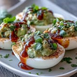 Vibrant deviled eggs with avocado filling and a zesty Sriracha kick, perfect for healthy party snacks or brunch.