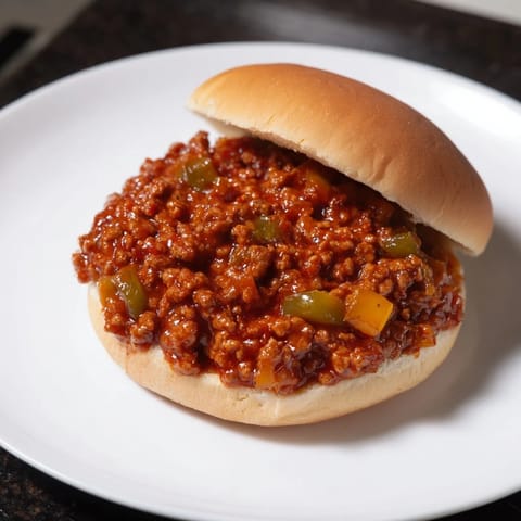 A close-up of a flavorful Sloppy Joe, savory ground beef filling the soft, golden buns.