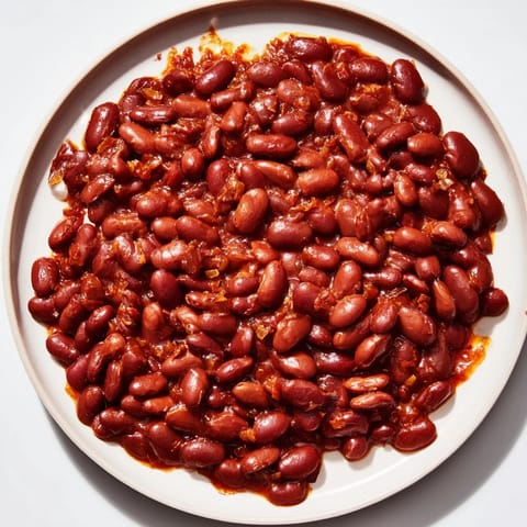 A close-up of savory baked beans, showcasing a rich tomato sauce and tender, cooked beans.