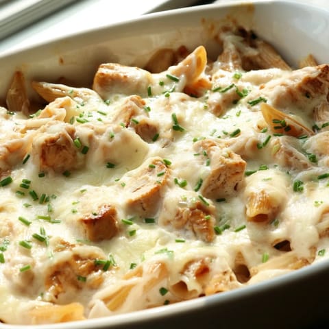 Steam rises from the cheesy Chicken Ranch Pasta Bake, revealing tender penne pasta and diced chicken in a creamy ranch blend.