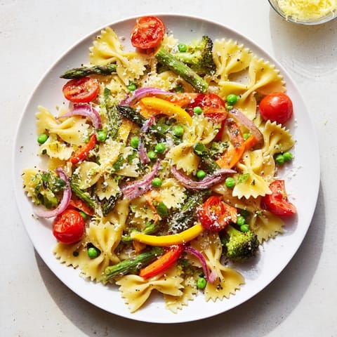 Freshly cooked Rainbow Veggie Pasta Primavera in a white bowl, showcasing colorful bow-tie pasta with vibrant spring vegetables and herbs.