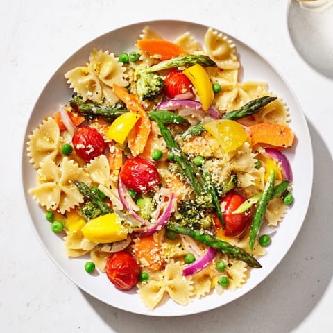 A close-up of steaming Rainbow Veggie Pasta Primavera, tossed with crisp asparagus, bell peppers, and a light garlic olive oil sauce.