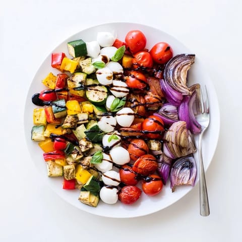 Caramelized roasted zucchini, bell peppers, and cherry tomatoes are tossed with mozzarella pearls and fresh basil for a vibrant Roasted Veggie Caprese Salad.